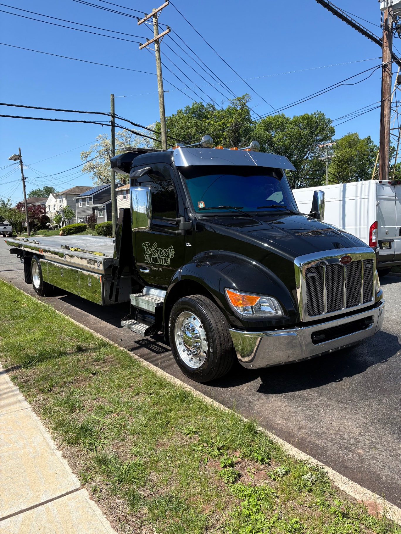 Black Peterbilt flatbed tow truck gleaming with deep gloss and polished chrome after detail