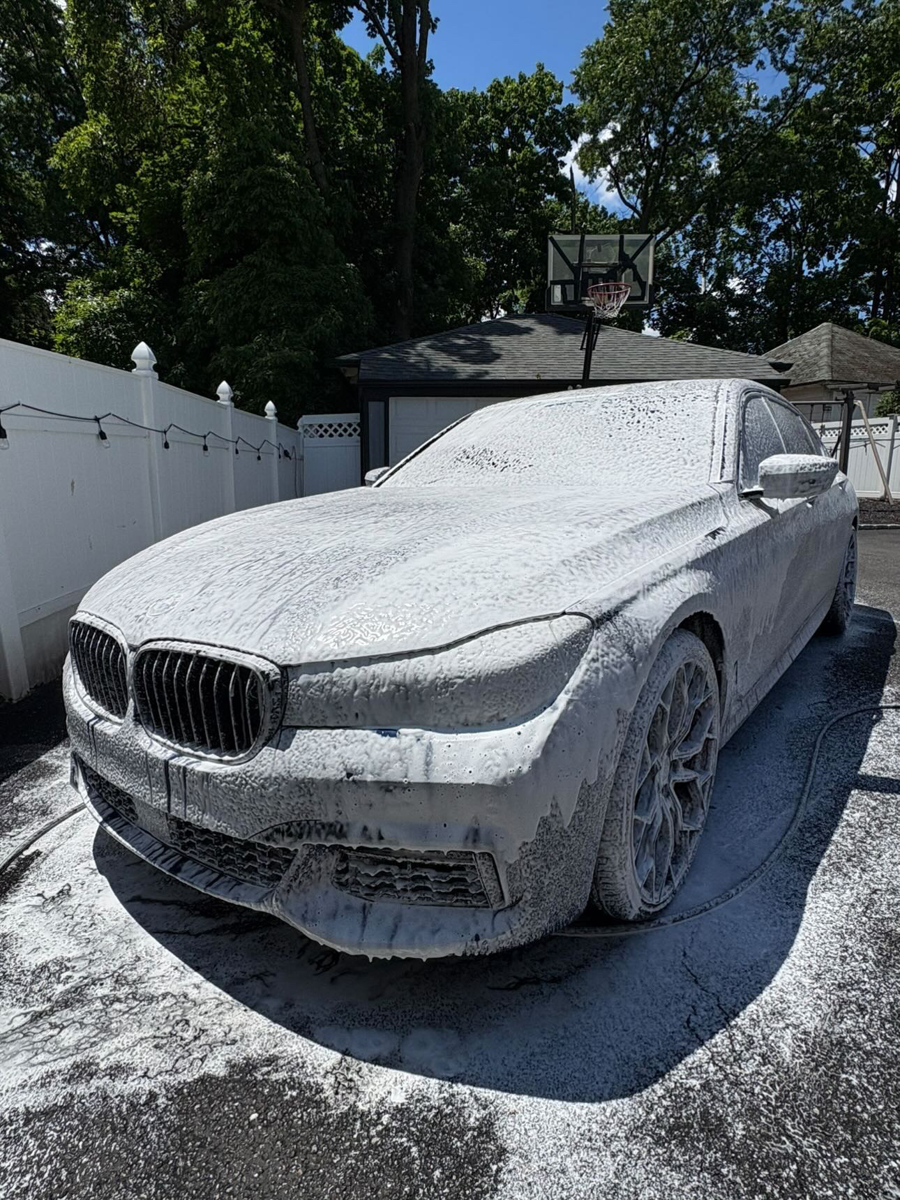 BMW 7 Series sedan covered in thick snow foam during pre-wash