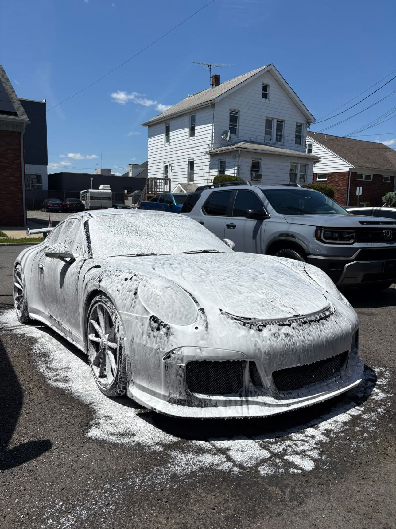Black Porsche 911 GT3 covered in snow foam during contact wash